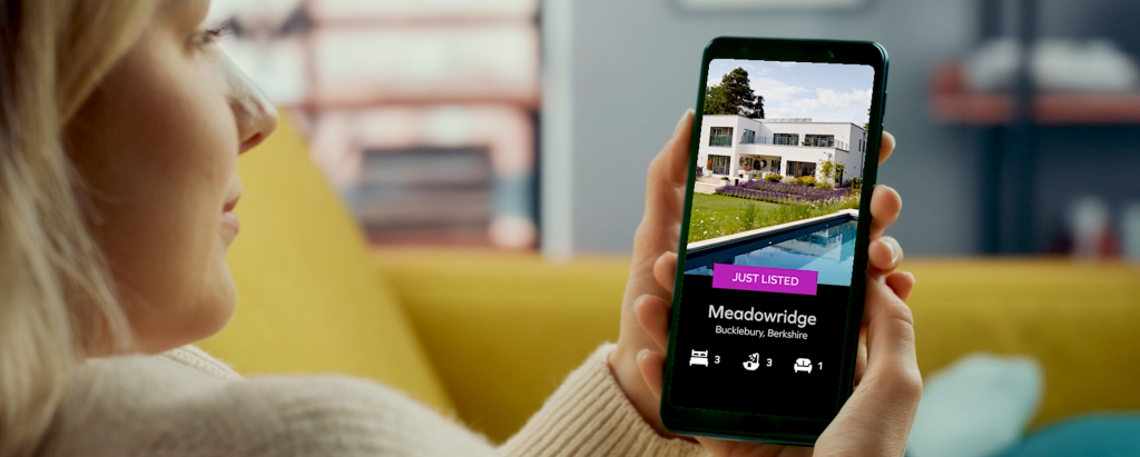 An image of woman watching real estate video on mobile highlighting importance of digital marketing for estate agents.
