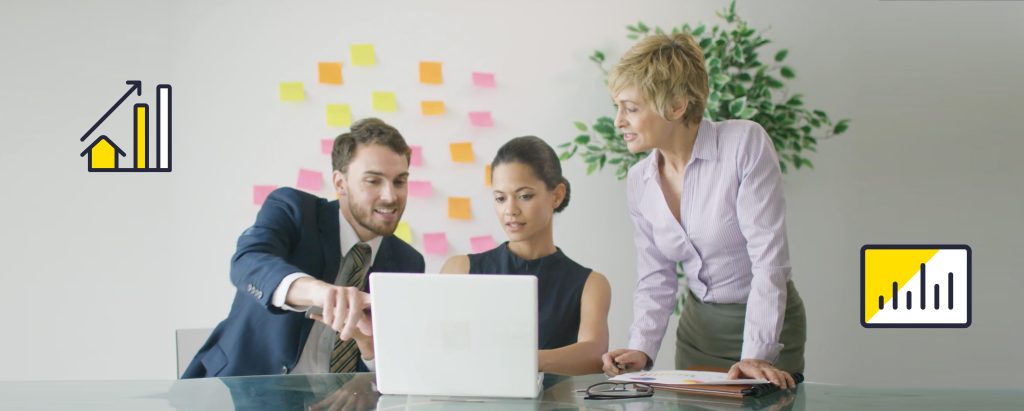An image of real estate agents around a computer looking at sales analytics.